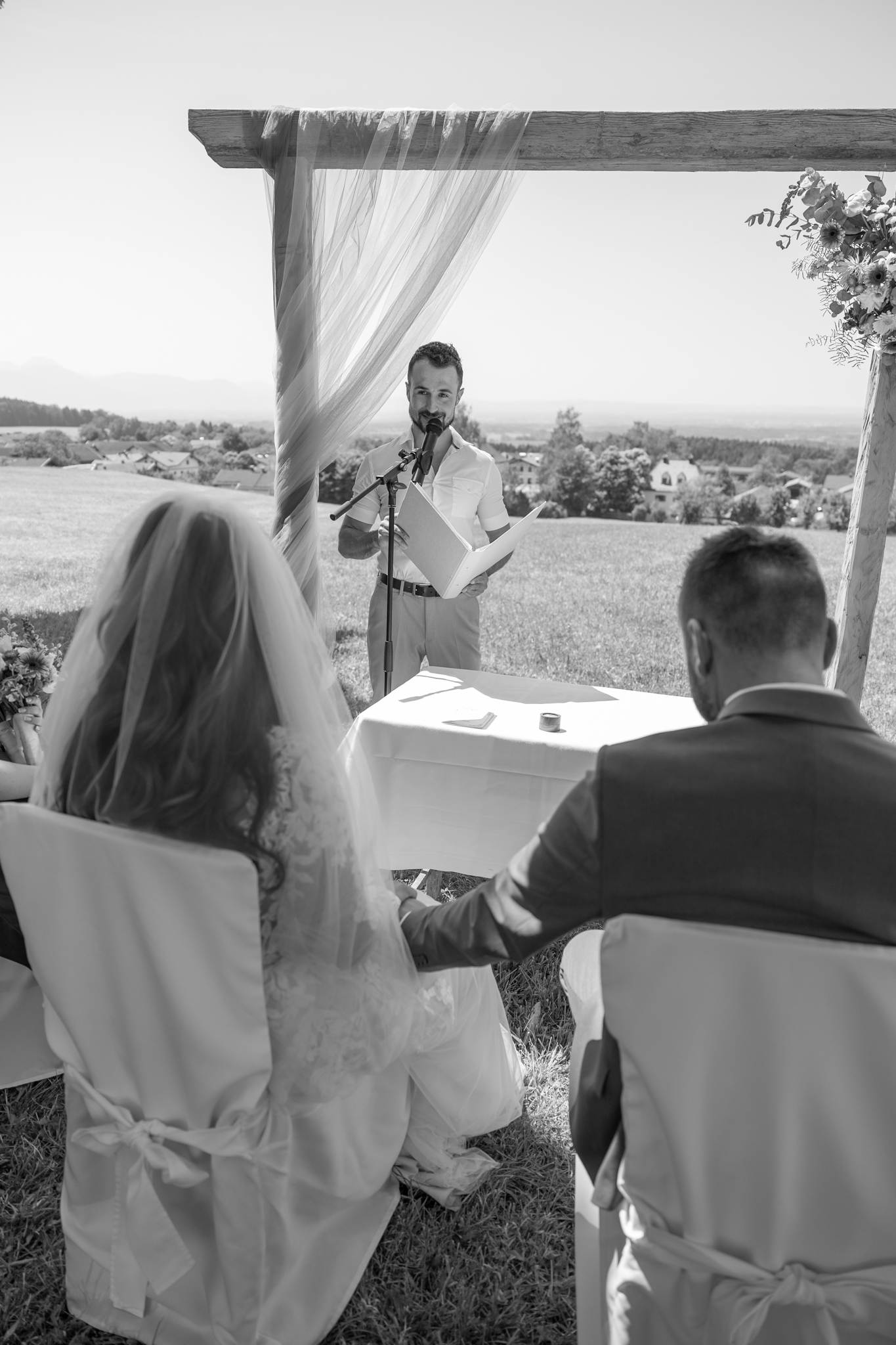 Schwarzweißfoto einer Trauung im Freien am Tisch vor dem Brautpaar
