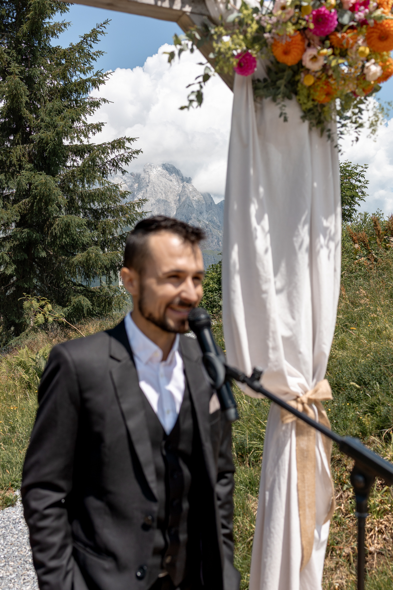 Redner am Mikrofon bei einer Trauung vor Bergkulisse